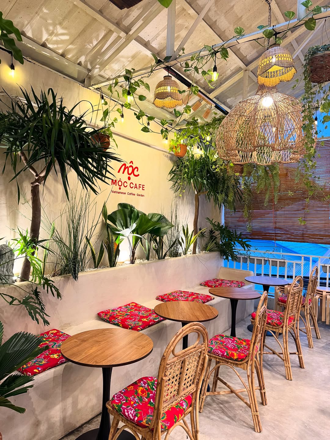 MỘC Cafe interior with lush plants and rattan seating