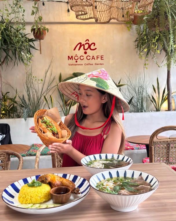Guest with Vietnamese hat holding Banh Mi at MỘC Cafe