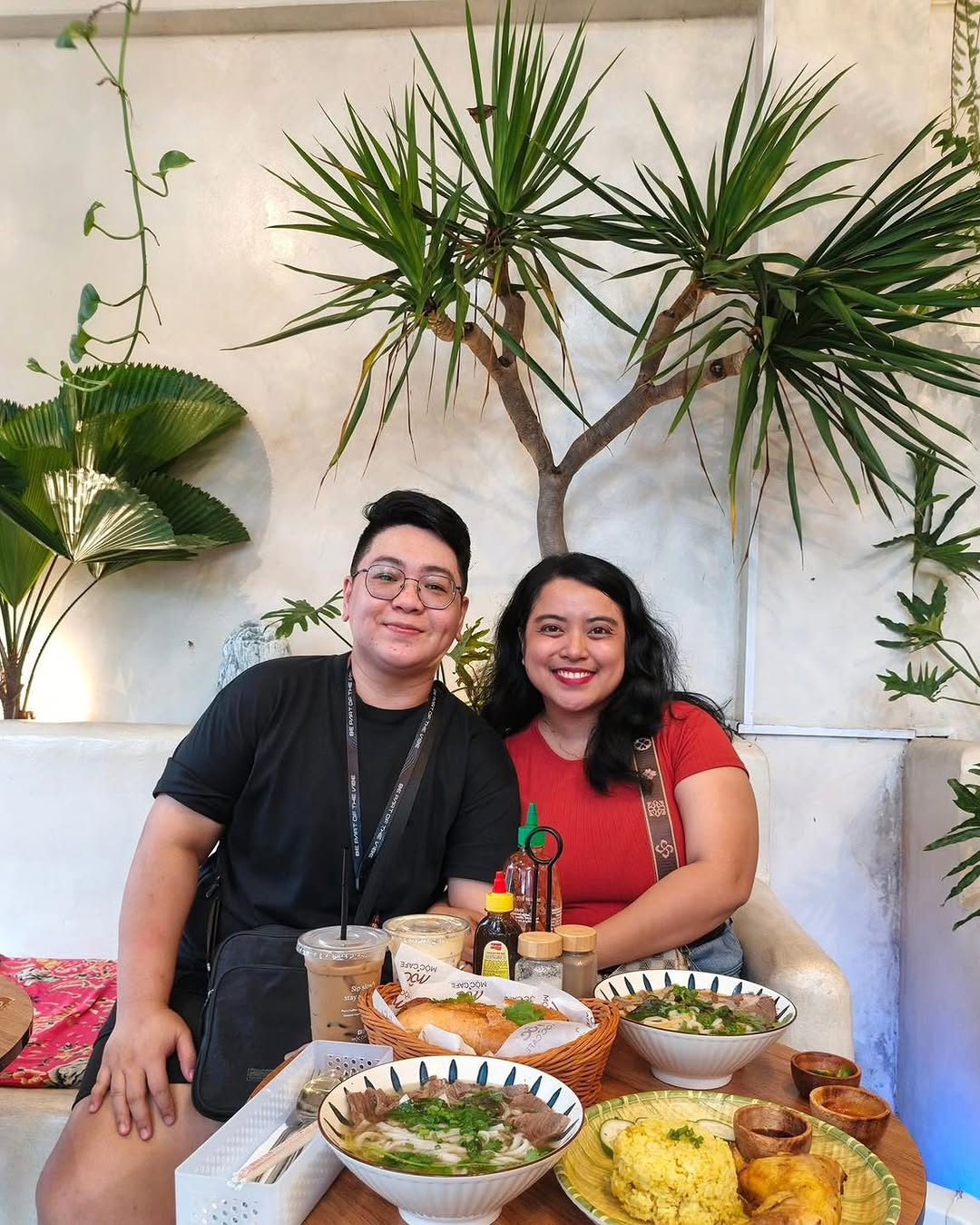 Couple smiling with Pho and food spread at MỘC Cafe
