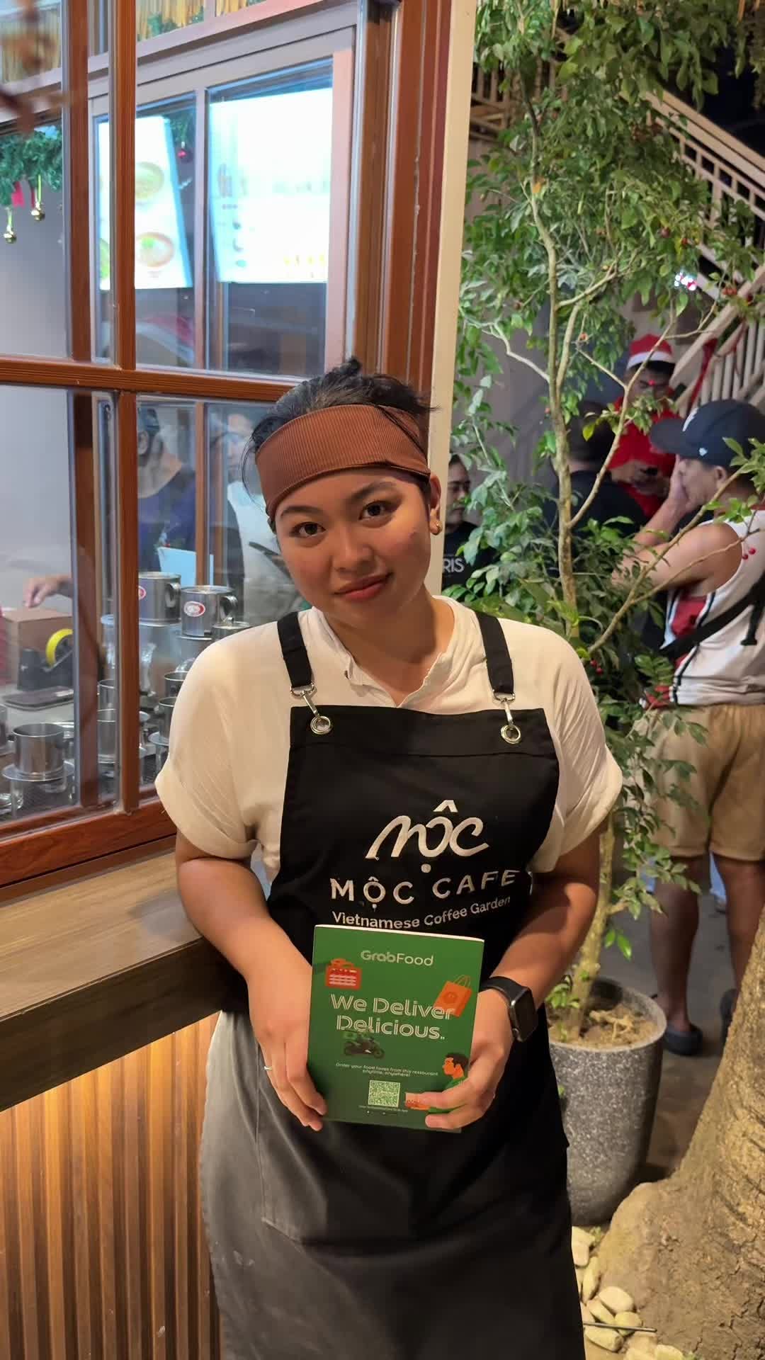 MỘC Cafe staff member holding Grabfood at kitchen window